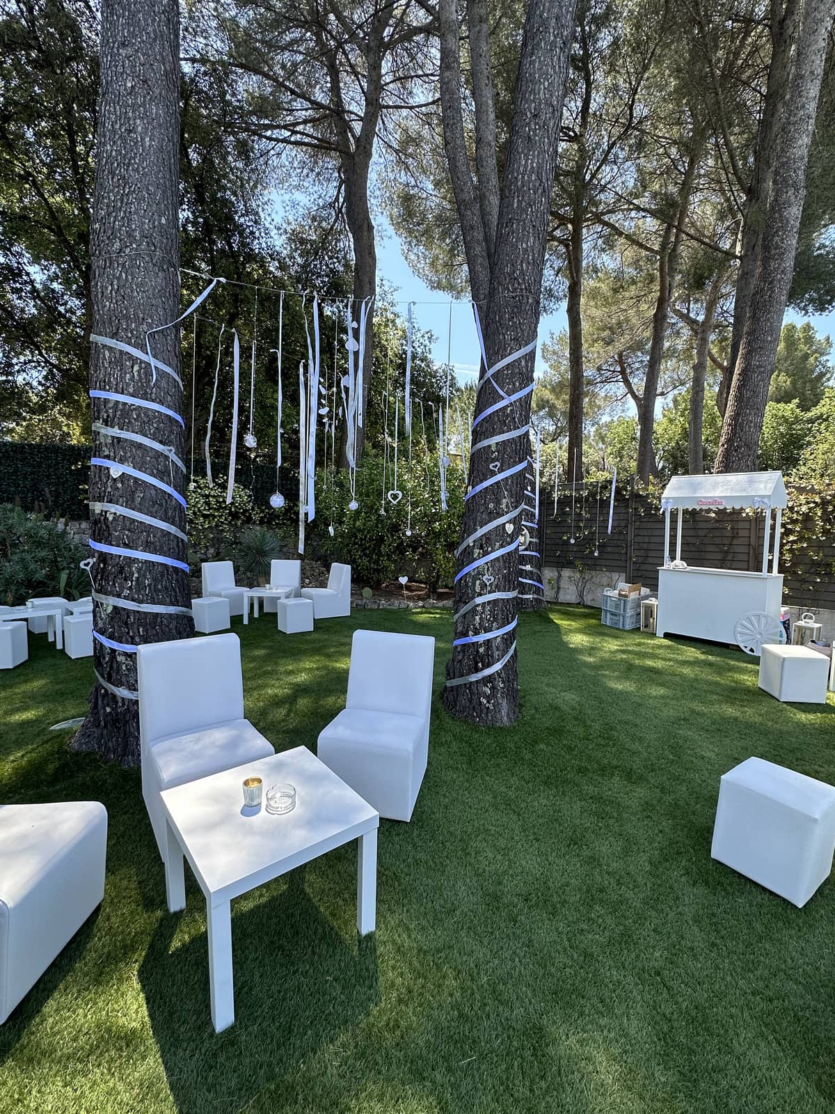 Chauffeuse événementielle blanche design, espace lounge extérieur ou intérieur avec tables basses et décoration suspendue, idéale pour mariages et événements haut de gamme sur la Côte d’Azur Agence évènementielle loueur de mobilier