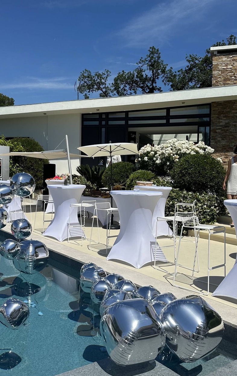 Tables mange-debout blanches avec housses, disposées en bord de piscine avec tabourets hauts, idéales pour cocktails, réceptions et événements haut de gamme sur la Côte d’Azur Agence évènementielle loueur de mobilier