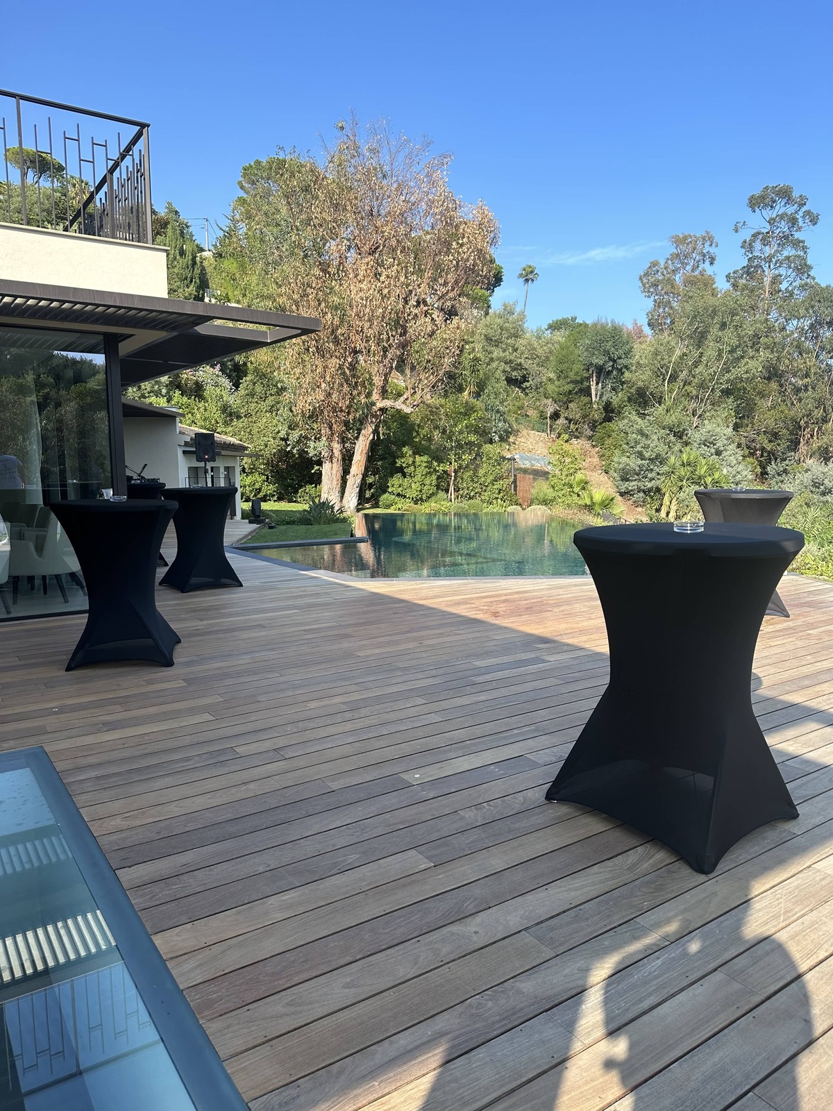 Table mange-debout noire avec housse, extérieur sur terrasse avec vue piscine, ou intérieur, idéale pour cocktails, réceptions et événements professionnels sur la Côte d’Azur Agence évènementielle loueur de mobilier